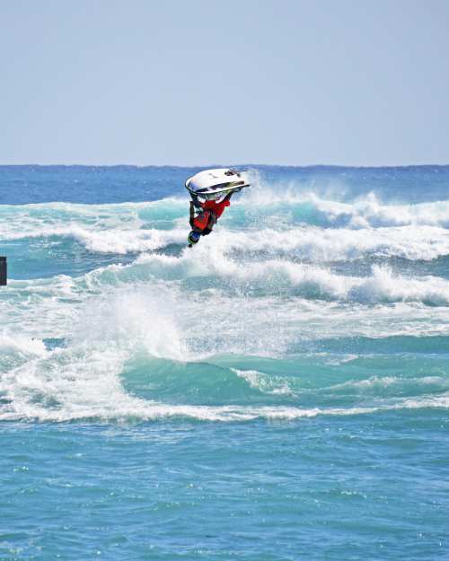 a man doing an aerial 360 flip on a jetski in the ocean waves of palm beach county