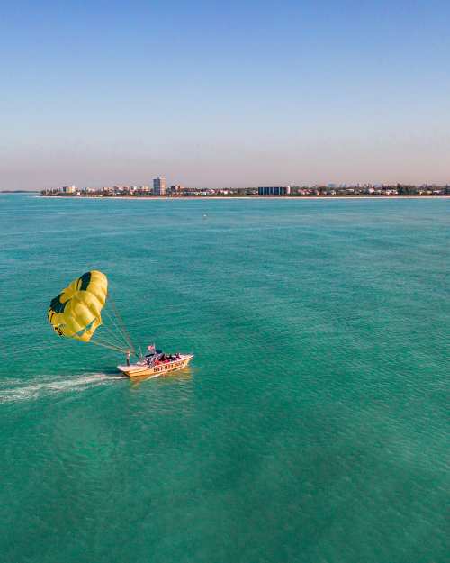 Parasailors lift off from the back of a boat off Siesta Key Beach in Sarasota County.y